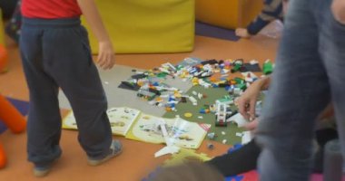 Küçük erkek öğretmen çocuklarla tarama ve Opole Merkez Kütüphanesi atölyesinde bir plastik oyuncak kurucu oynarken yürüyüş katta oturuyorsun