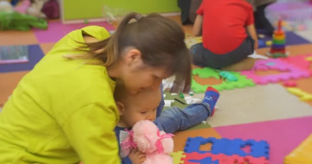Małe dzieci siedzą na podłodze i gry plastikowe zabawki Konstruktor nauczyciel daje zabawki chłopca w centralnej biblioteki warsztaty w Polsce opolskie — Wideo stockowe