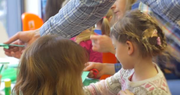 I bambini stanno lavorando con la carta colorata che fa un insegnante del giocattolo di carta aiuta il laboratorio centrale dei giocattoli della biblioteca dei bambini a creare — Video Stock