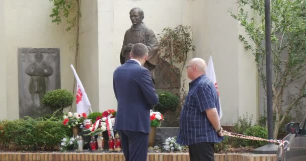 Dwaj starsi mężczyźni stoją i rozmawiają na statua papieża kwiatów rzymskich w Memorial Service w katedrze Kościoła w Opolu Kraków Street — Wideo stockowe