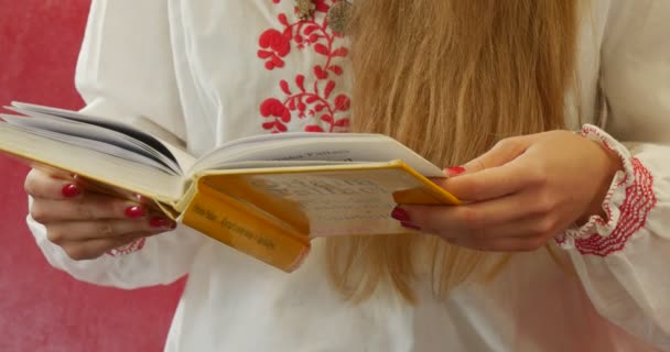 Ung kvinna läser boken i City Public Library kvinnan i vit broderad skjorta med röda mönster inomhus Opole Polen — Stockvideo