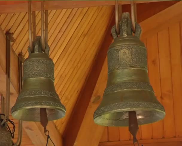 Två klockor kupoler på ortodoxa kyrkan kapell Bells kupoler under taket kupoler av gula metallen logga träbyggnad religiösa objekt — Stockvideo