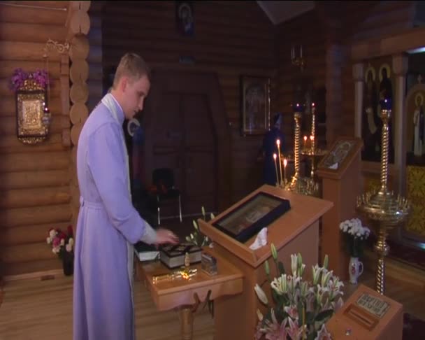 年轻男人神职人员在紫服装是站准备在东正教宗教图像 Caldles 儿童洗礼仪式 — 图库视频影像