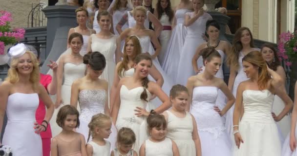 Multidão de noivas mulheres em vestidos brancos de diferentes estilos Poucas linhas de modelos estão posando e sorrindo na frente da câmera de pé em uma menina de escadas em rosa — Vídeo de Stock