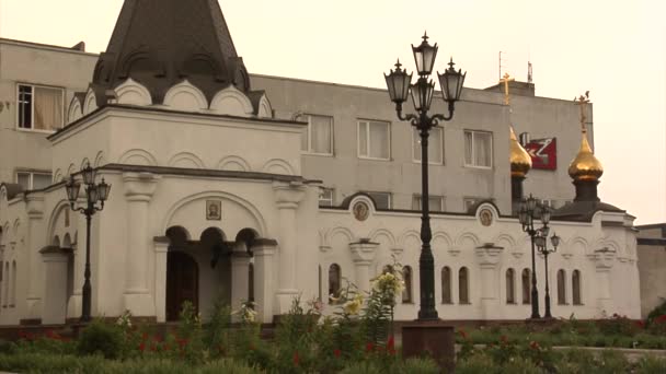 Witte gebouwen van een tempel gouden koepels straat lampen steegje aan de kerk in de metallurgische fabriek grondgebied op de kolen mijne Donetsk bewolkte dag — Stockvideo