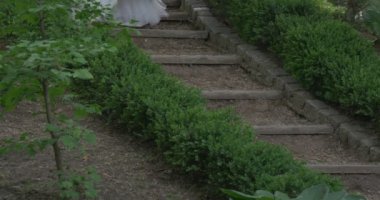 Yürüyüş aşağı yavaş yavaş poz fotoğraf makinesi gelinler Parade önünde beyaz kılıf elbise ile uzun kırmızı kemer yüzsüz bir çerçeve kızın gelin kadın mı