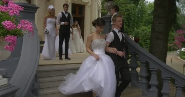 Paren bruiden en bruidegoms zijn lopen beneden vrouw in witte jurk Man in kostuum Vest en Bow Tie vrouw houdt een Parade praten met microfoon — Stockvideo