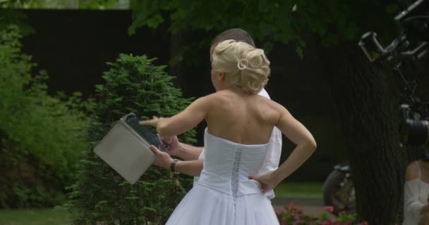 Mulheres de vestido branco noiva e homens câmera equipe ensaio noivas desfile no parque verde As pessoas estão olhando para a câmera Euqipment do operador de tela Tablet — Vídeo de Stock