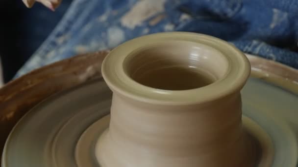 Potter Craftsman está ensinando uma mulher a trabalhar na roda de cerâmica segurando sua mão mostrando como moldar um vaso de barro fazendo um vaso Mãos masculinas e femininas — Vídeo de Stock