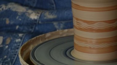 Potter Kadın Craftsman Spatula Dirty Hands Close Up Man tarafından Çömlek tekerlek Cam üzerinde Dönen bir Pot Boyama Camlı Olduğunu Jeans Oturur Çömlekçilik Atölyesi