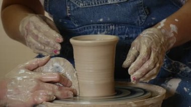 Potter Craftsman Çömlekçi tekerlek üzerinde çalışmak için Öğrenci Yardımcı Olur Bir Şey Spatula Dirty Hands Close Up Çömlekçilik Atölyesi ile Bir Kil Pot Kalıplama Açıklar