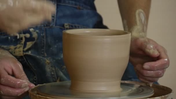 Potter kvinnliga hantverkare i gul T-Shirt undervisning en Student arbetar på Pottery Wheel att forma en lera potten smutsiga händer nära upp mannen handtvätt en — Stockvideo