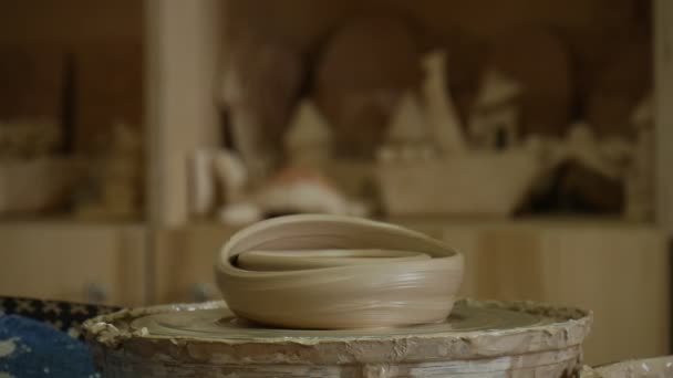 Homem ou mulher Potter Craftsman em Jeans Avental está trabalhando em uma roda de cerâmica enrugada Pot em uma roda Oficina de cerâmica Produtos de argila em uma prateleira — Vídeo de Stock