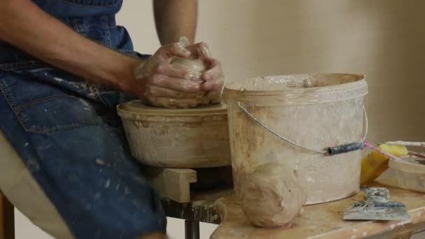 Τεχνίτης Πότερ στην ποδιά τζιν είναι εργασίας κάνοντας κατσαρόλα σε περιστρεφόμενο τροχό αγγειοπλαστικής το τροχό γρήγορα πιέζοντας το πήλινο χύτευση ένα εργαστήριο πηλού σουβενίρ — Αρχείο Βίντεο