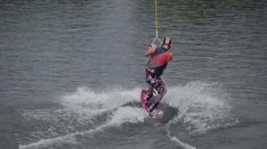 Kask ve su kayağı kostüm su kayağı kayakçı erkekte su kablo çeker banka ağaçlar uyku modundan çıkarma Park kadına Kayak adam kablo alır.