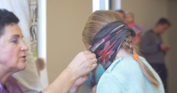 Pedagógus nő van Blindfolding a lány előtt a játék ad neki egy Játékszer Csoport gyereknek játszik egy időben egy óvoda osztályteremben — Stock videók