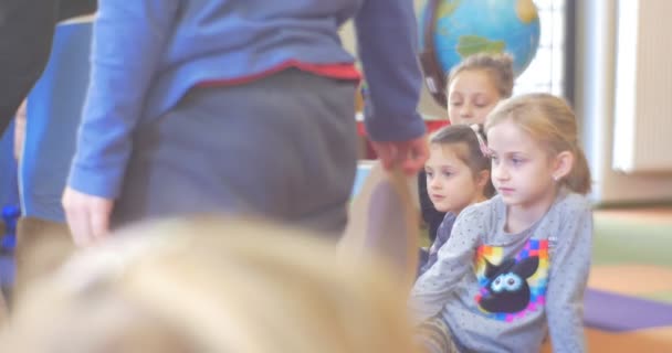 Gruppo di bambini Bambini Ragazzi Le ragazze sono sedute su un pavimento guardando davanti a loro che giocano si divertono in una classe della scuola della biblioteca — Video Stock