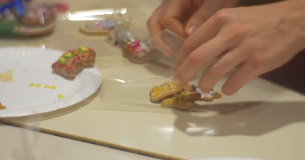 Les mains mettent et emballent quelques biscuits de Noël dans un polyéthylène Les enfants font des biscuits du Nouvel An ensemble à la maternelle ou à la maison — Video