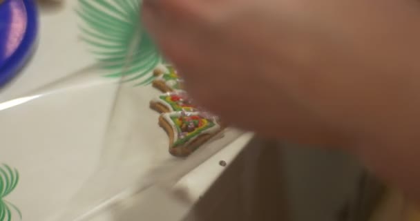 Las manos de los niños están empacando una galleta de Navidad en forma de árbol de abeto en un polietileno Los niños están haciendo galletas de año nuevo juntos en el taller de en casa — Vídeos de Stock