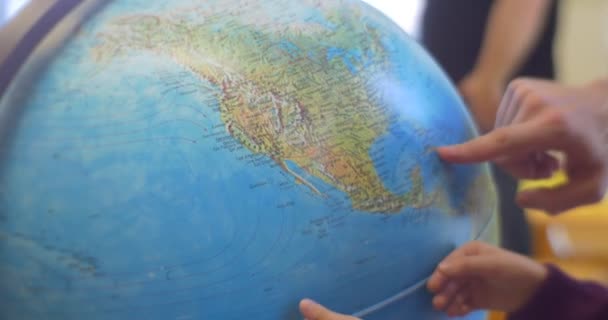 Little Blonde Girl With Long Hairs Kid And Dad Hands Close Up are Standing at a Globe Rotating the Sphere Looking at Continents Curious Child in Library — Stock Video