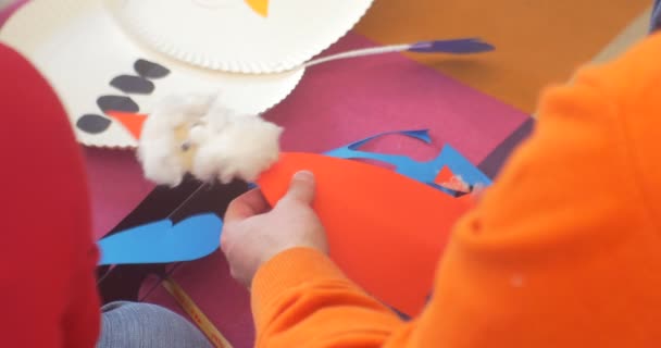 孩子持有贴花圣诞老人的红外套胡子两个孩子都坐在制作雪人的一次性盘子和纸新的一年的贴花 — 图库视频影像