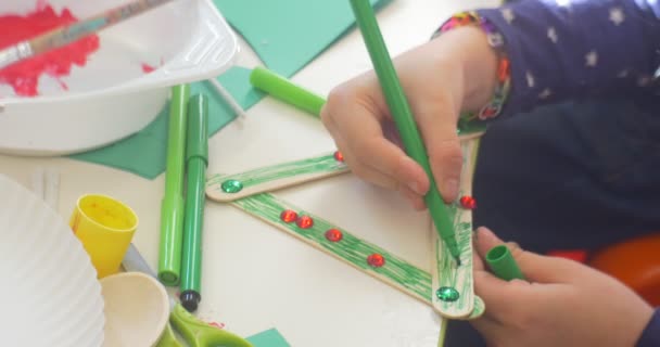 子供は着色緑マーカー Rhinrstores で装飾的な三角形三角形子供の上にある手クローズ アップその他子供が作るアップリケ塗料カット紙 — ストック動画