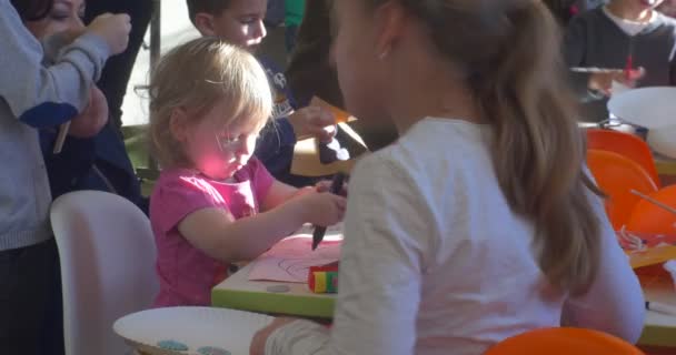 Niños de diferentes edades están pintando y cortando papel sentados a la mesa haciendo electrodomésticos de invierno de año nuevo en un salón de clases de kindergarten — Vídeos de Stock