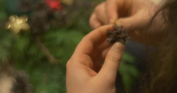 La mujer adulta está enderezando un cono de abeto y agregándolo cuidadosamente a la composición navideña de las ramas de la corona de Adviento en la clase magistral de Año Nuevo de la mesa — Vídeos de Stock