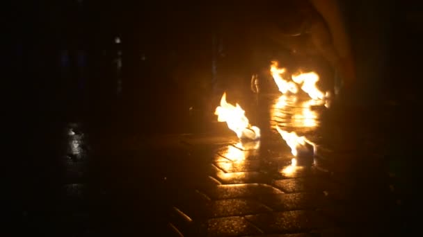アーティストは、火のショーで火のダンスの危険なトリックを実行した後、舗装された正方形のダンス劇団が歩いている弓燃焼トーチを取っています — ストック動画