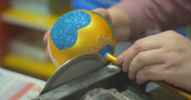 Handwerker schleift einen Glasstiel aus Spielzeug goldene Glaskugel von einer Schleifmaschine dekoriert Spielzeugmann packt das Spielzeug in eine Pappschachtel — Stockvideo