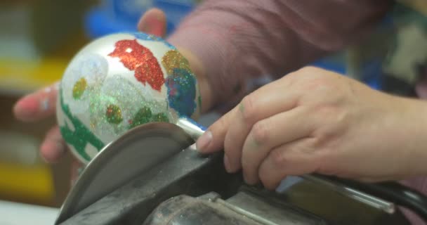 El hombre blanco brillante de la bola está aserrando hacia fuera un paquete de la bola del juguete de la Navidad de la manija en una caja de papel y da el juguete a una persona que lo hizo en la clase maestra de la familia — Vídeos de Stock