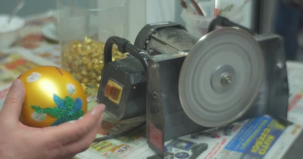 Человек распиливает ручку рождественского игрушечного мяча в бумажную коробку и дает золотую игрушку человеку, который сделал это на семейном мастер-классе — стоковое видео