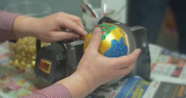 Goldener Kugelmann sägt an einem Glas Kugelstiel Weihnachtsspielzeug und bereitet sich darauf vor, das Spielzeug einer Person zu geben, die es beim Familienmeisterkurs in Oppeln geschafft hat — Stockvideo