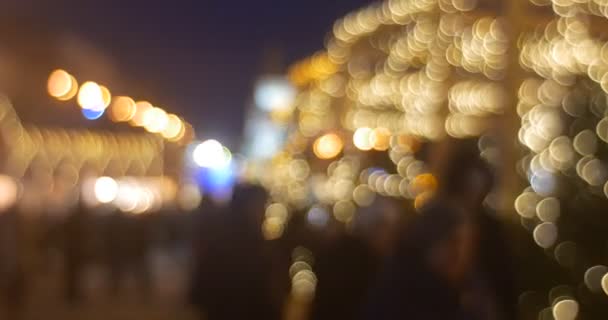 Las personas borrosas están caminando por el callejón de los abetos hacia las luces de la torre del reloj iluminadas por la cámara Brillantes guirnaldas en la plaza de Sofía Año Nuevo Kiev Ucrania — Vídeo de stock