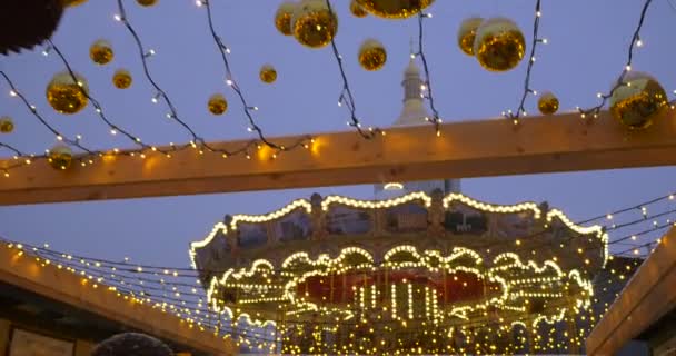 Giostra illuminata decorata con lampade Palline di Natale dorate Ghirlande su un cavo fissato su un campanile di Sofia Piazza Kievan — Video Stock