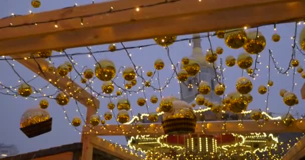 Chodzenie ludzie oświetlone karuzela ozdobione lampami złote Boże Narodzenie kulki Lampa Garlands na kablach dzwonnica Sofii Kievan na Sophia Square — Wideo stockowe