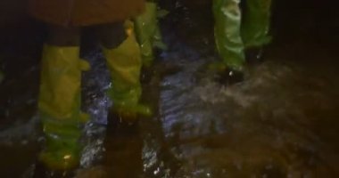 Yeşil Gumboots turist grubudur yürüyüş insanların çoğu tarafından su akışı bir mağara su yağmurlama yolu lamba ışığında yeraltı tarafından yaktı yürüyor