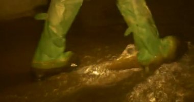 Bacaklar Gumboots turist diğer adam için bir mağara bacaklar yaktı lamba ışığında karanlık kişi yaklaşımlarla içinde bir su akışı Underground nehir kenarındaki yürüyüş.