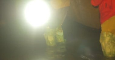 Erkekler Eski Bir Boru Işığına Yaklaşımlar Tüp Diz-Deep Underground River Erkekler Bir Mağara turistler dikkatle yürüyorlar Su ile Wading vardır