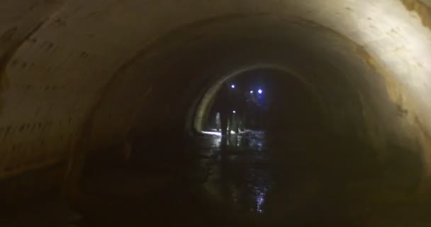 Touristen Licht blendet das Auge Menschen sind zu Fuß durch eine Höhle Menschen erkunden eine Höhle mit Stirnlampen kleinen Bach Wasser Strom Neujahrsausflug — Stockvideo