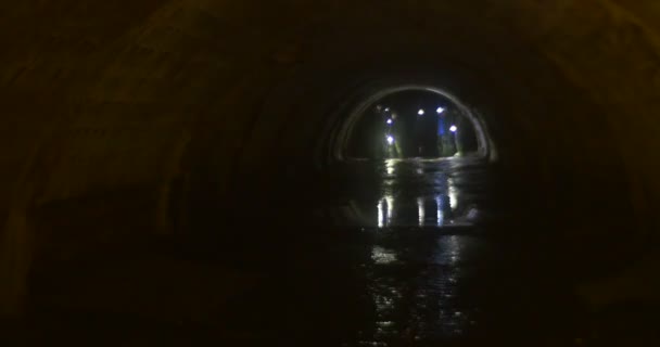 Les touristes marchent par les lumières de la grotte La façon dont les gens explorent une grotte avec des phares debout dans un ruisseau d'eau Les gens regardent les murs d'un tunnel 