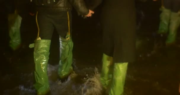 Piernas de Turistas Primer plano Pareja sosteniendo las manos Grupo está vadeando en una cueva oscura por un pequeño arroyo de agua La gente ilumina el camino por una Excursión de Lámparas Año Nuevo — Vídeos de Stock