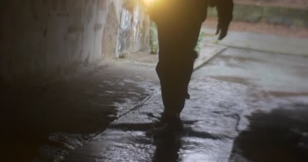 Man's silhouet loopt in een grot met lamp lichten de weg voor hem andere toeristen zijn buiten bij de ingang van een grot voor de excursie — Stockvideo