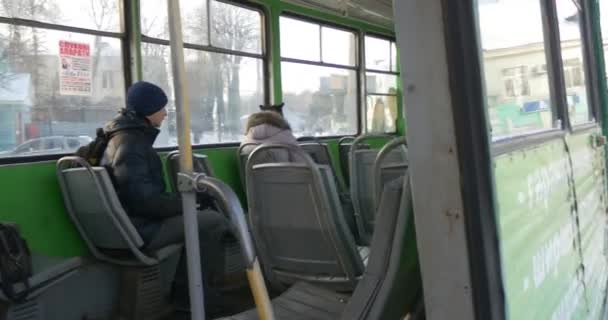 Lidé čekají na odjezd tramvají sedící sedadla ve voze staré zelené tramvaje na železnici zimní budovy holé větve stromy Cityscape Vánoce — Stock video