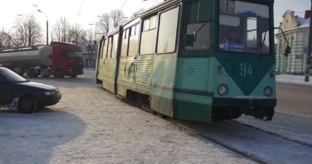 Grüne Straßenbahn kommt zu einem Bahnhof Menschen warten auf eine Straßenbahn am Bahnhof alte Straßenbahn bewegt sich durch eine Eisenbahn Winter Gebäude kahle Äste Bäume Weihnachten — Stockvideo