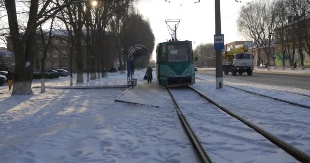 人々はトラムワゴンを取っている人々は、人々が通りを歩いている古いトラムは鉄道冬の建物裸の枝の木のクリスマスに移動しています — ストック動画