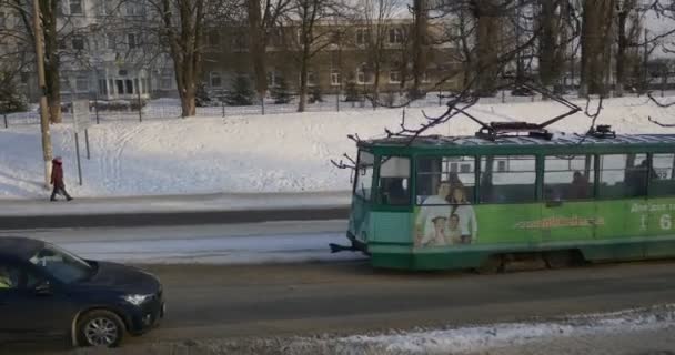 Zelená tramvaj je pohybující se městský Panorama chodci lidé chodí pěšky po ulici stará tramvaj, která se pohybuje po železniční zimní budovy holé větve stromů — Stock video