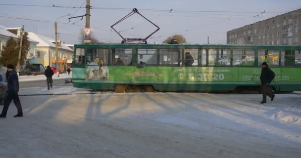 Panorama unui vagon pietoni oameni care așteaptă plecarea tramvaiului Oamenii merg pe jos cu un tramvai vechi de stradă la gara de tramvai Clădiri de iarnă Copaci — Videoclip de stoc