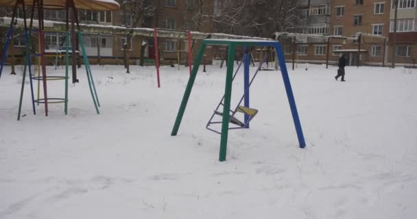 Az ember sétál át a Yard swing lengő sandbox játszótér berendezések borított Snow gyerekes játszótér télen Residental házak sok hó — Stock videók