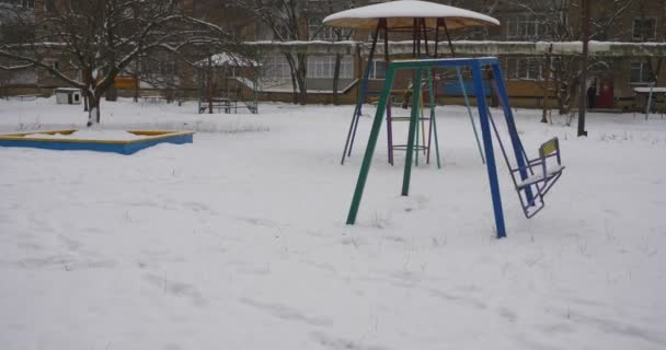 Metal Swing está balançando Sandbox Playground equipamentos cobertos com neve infantil playground sem crianças no inverno casas residenciais grande parte da neve — Vídeo de Stock